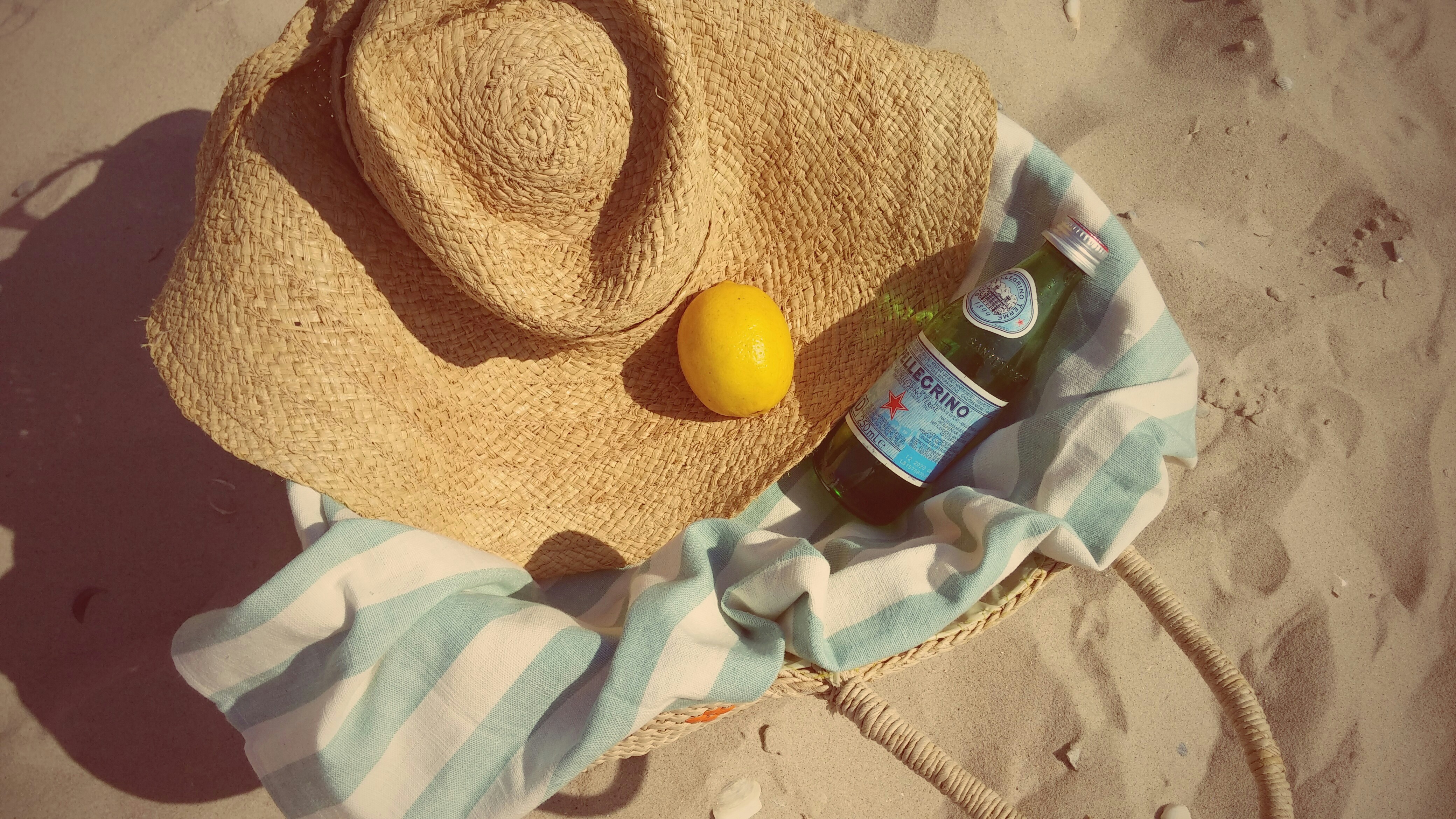 A sober summer with a beach hat, blanket, and mineral water