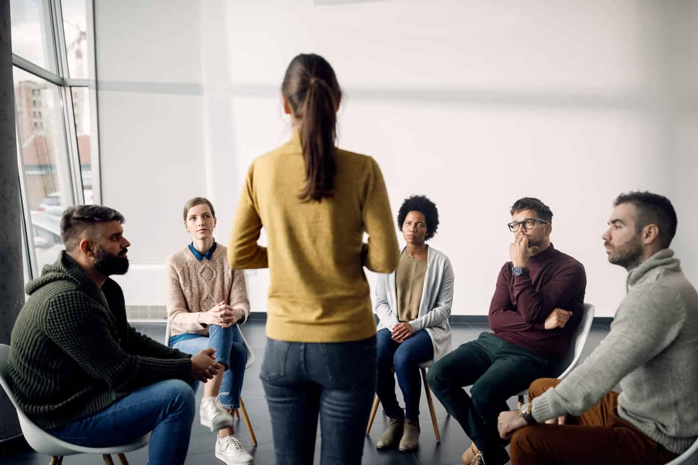 Diverse people listening to a woman during support group meeting at Mountainside Treatment Center