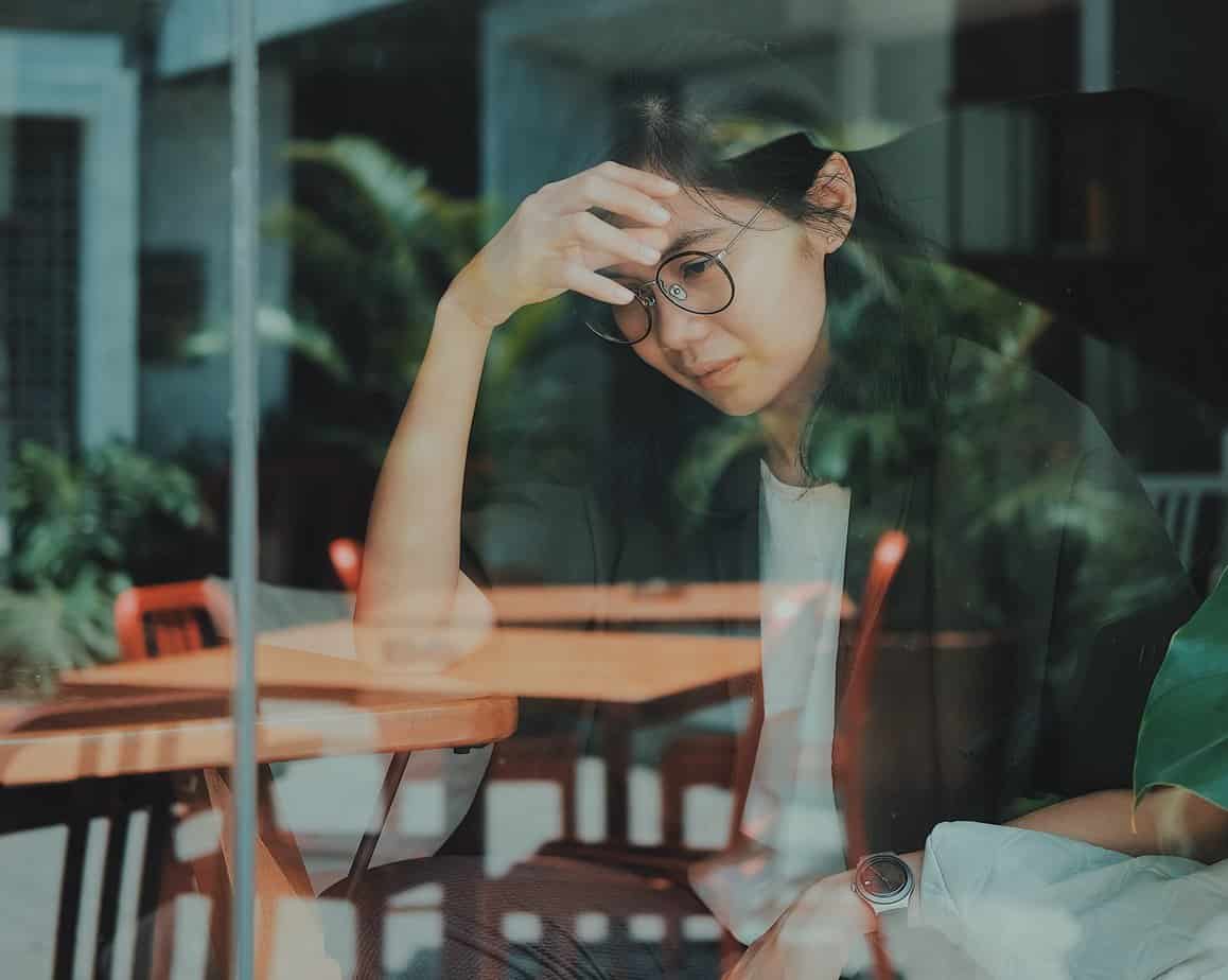 woman in glasses ponders idea of detox vs rehab