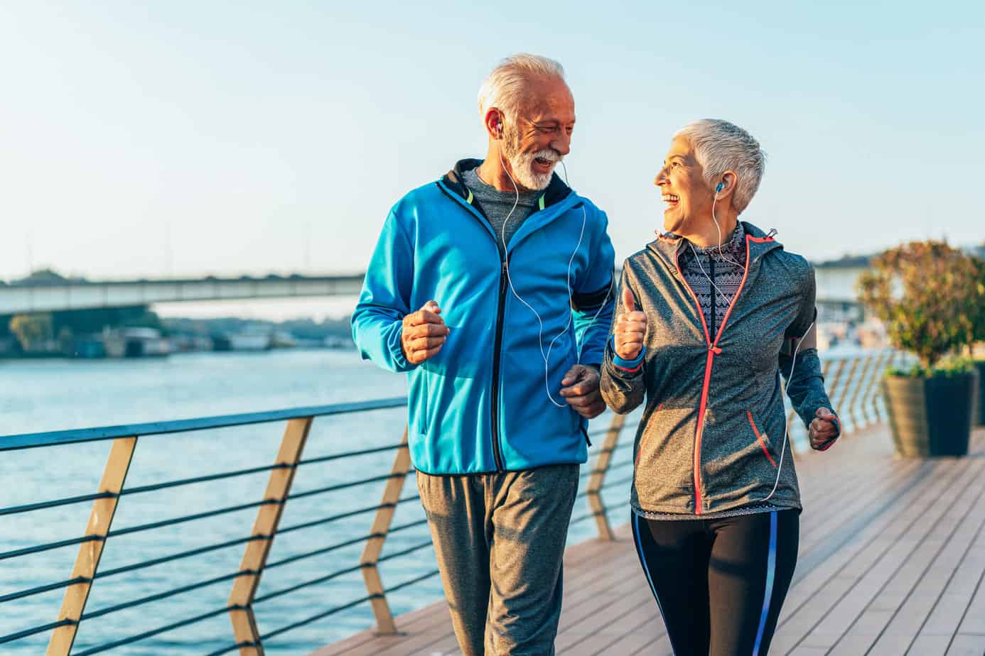 old couple jogging on seaside boardwalk as a form of self-care and to help their mental health