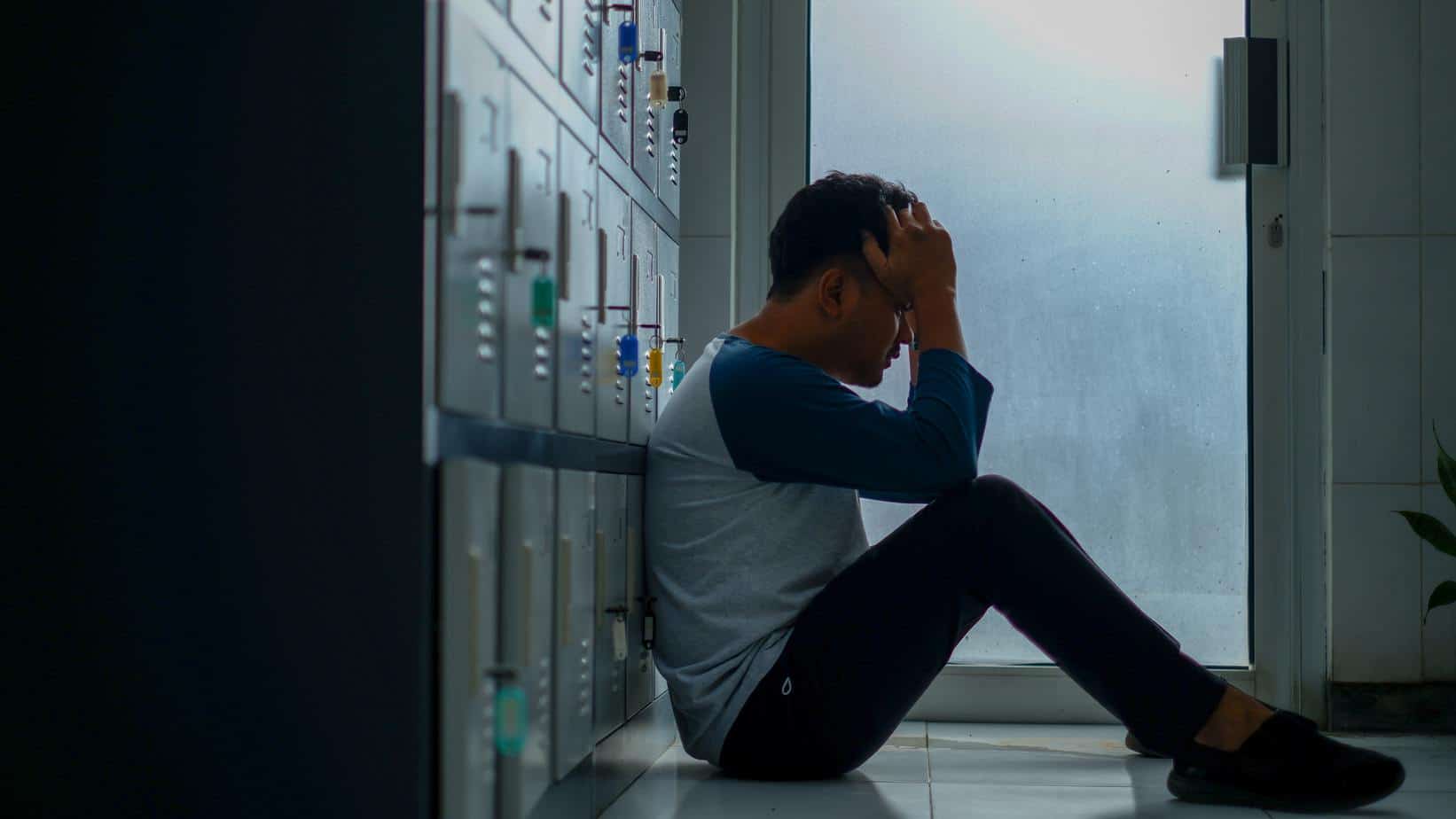 Stressed Teenager sitting on the floor with hands to his head