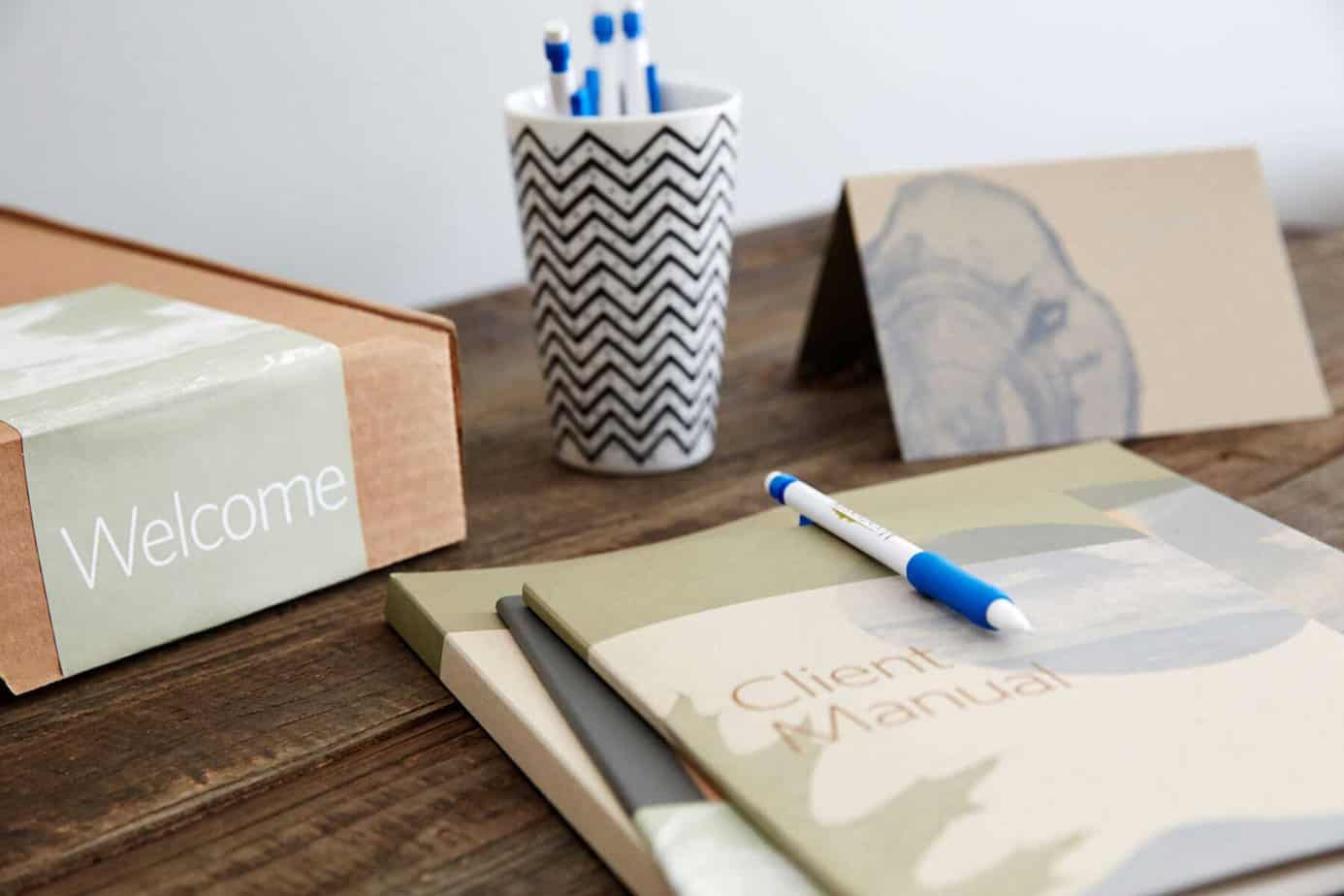 A Mountainside addiction treatment center welcome packet set up on a wooden table with a cup of pens.