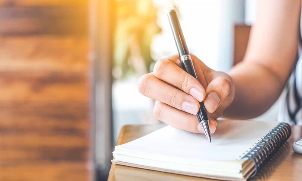 Close up of patient expressing feelings writing in notebook during expressive therapy