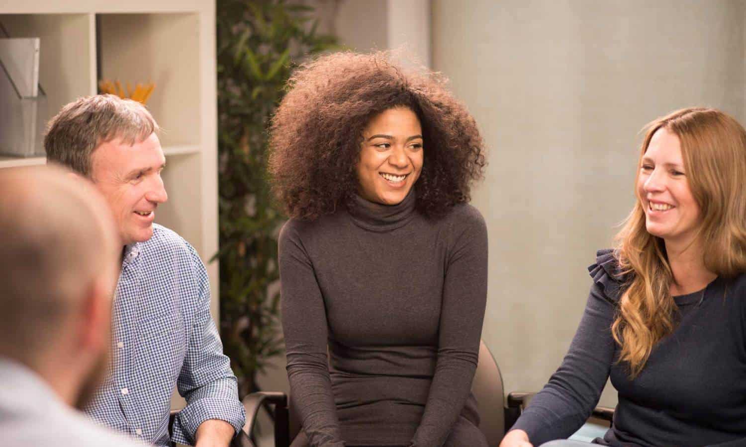 Woman smiling sitting in middle of group counseling session