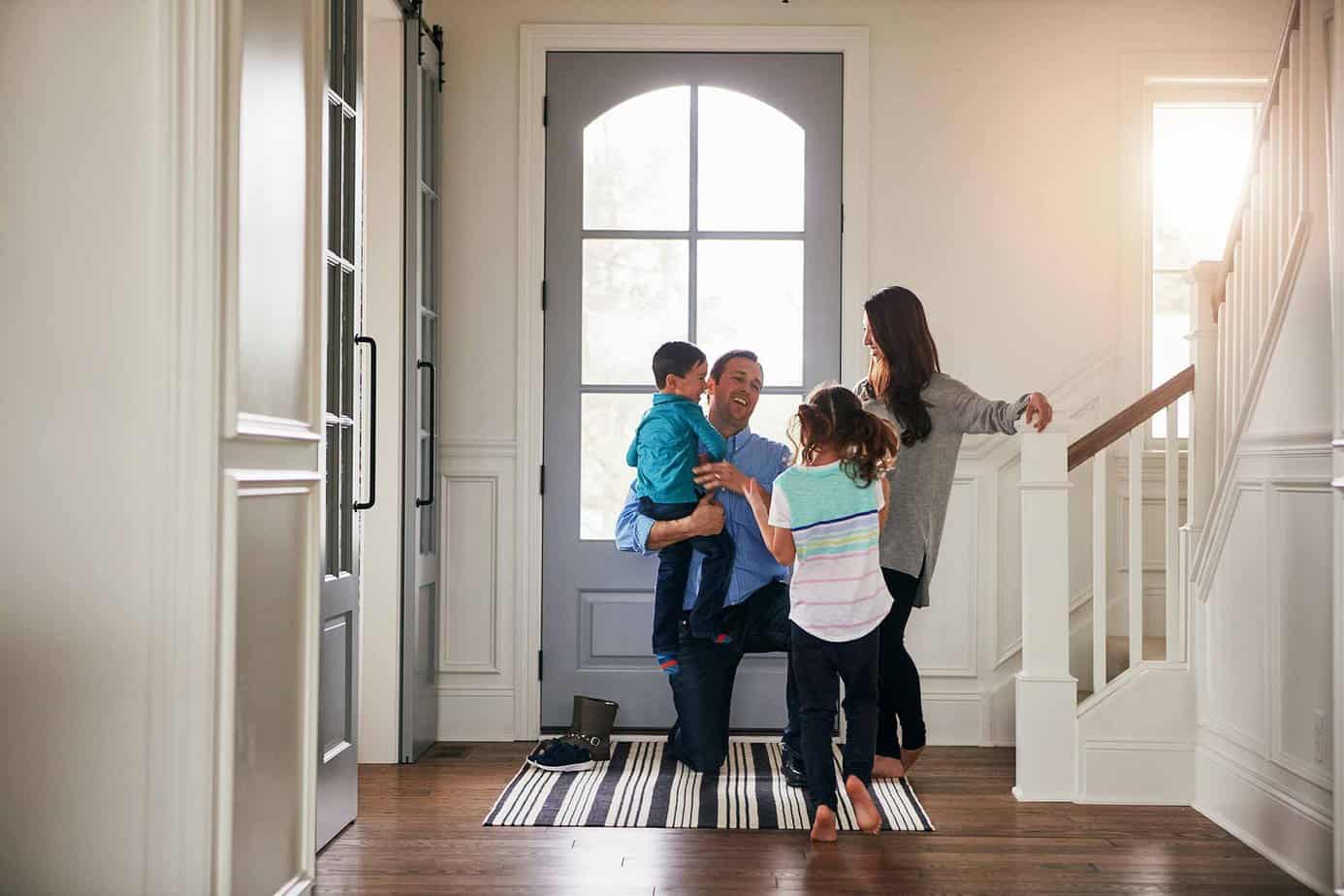 daughter son mother and father smiling in doorway of house