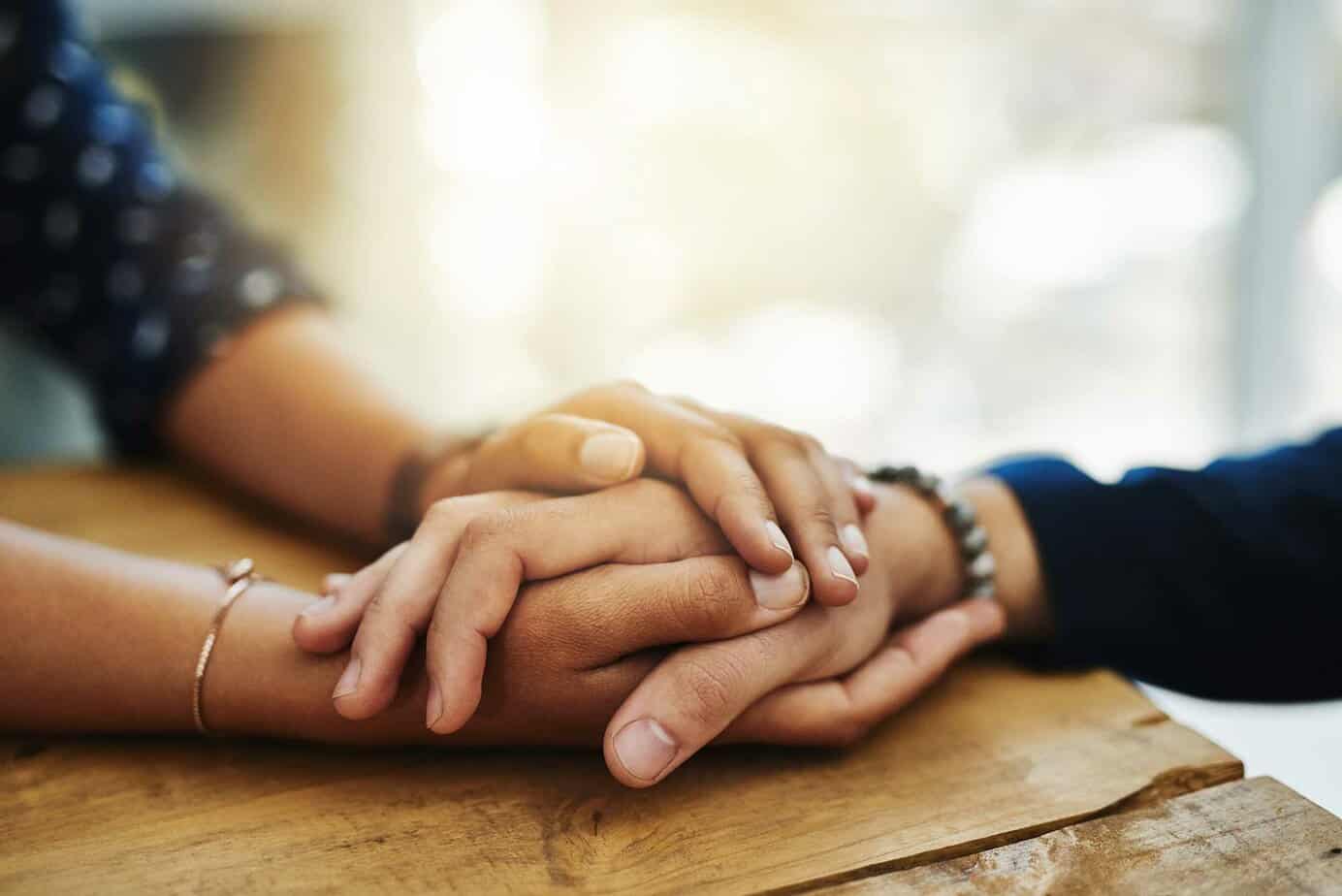 A woman takes a man’s hand as he prepares for drug recovery treatment