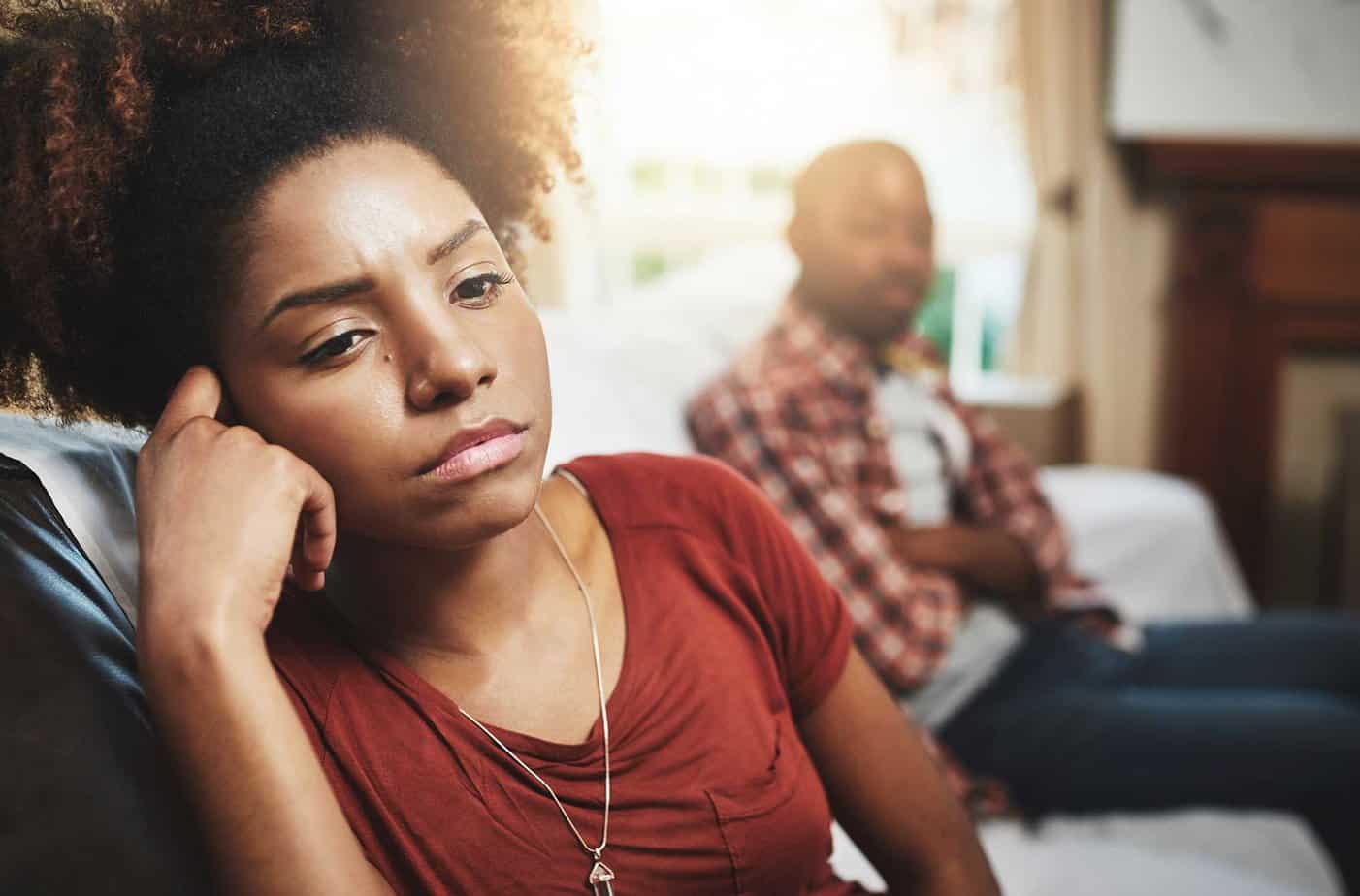 sad woman facing away from upset male on couch