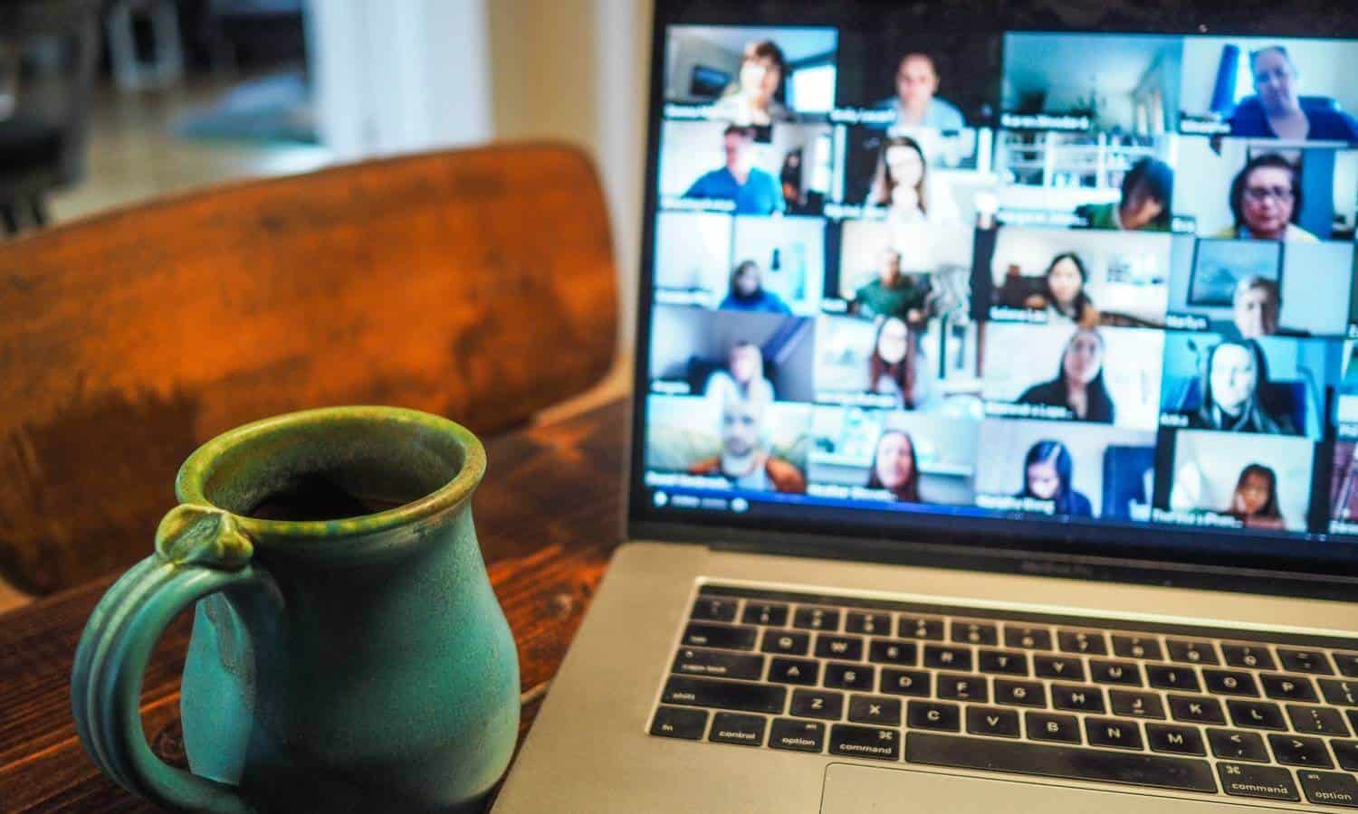 Laptop with Zoom meeting open and coffee mug on table.