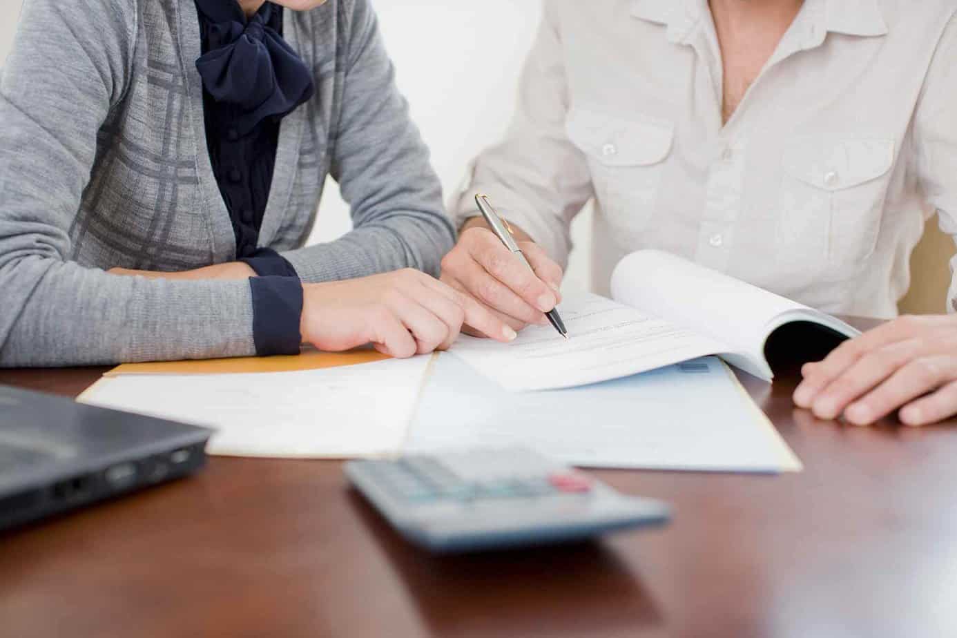 Two individuals reviewing legal documents together and making notes in the margins