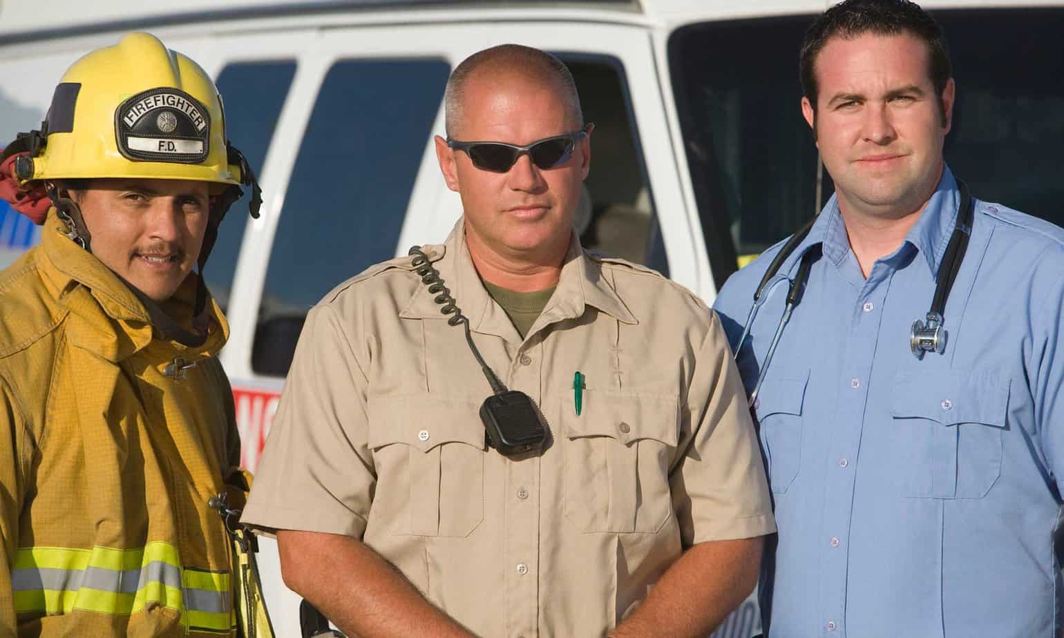 Firefighter EMT and police officer behind emergency van