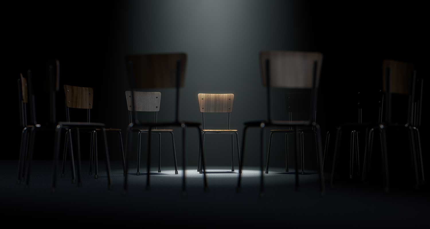 empty wooden chairs in a circle with stage light on center