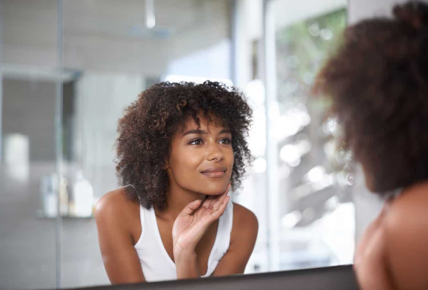 woman looks in mirror seeing the benefits of quitting drinking