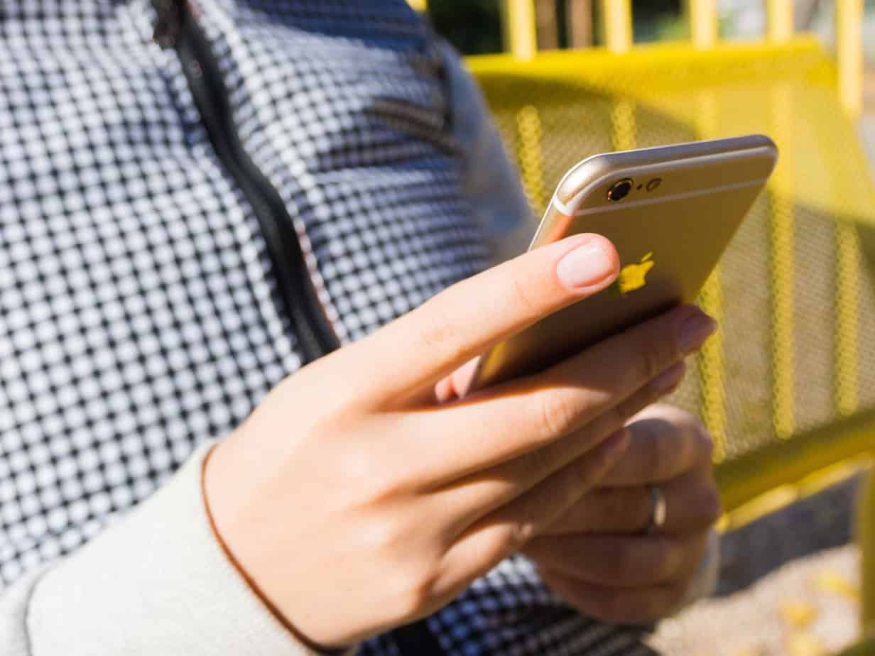 close up of hands holding iphone while texting