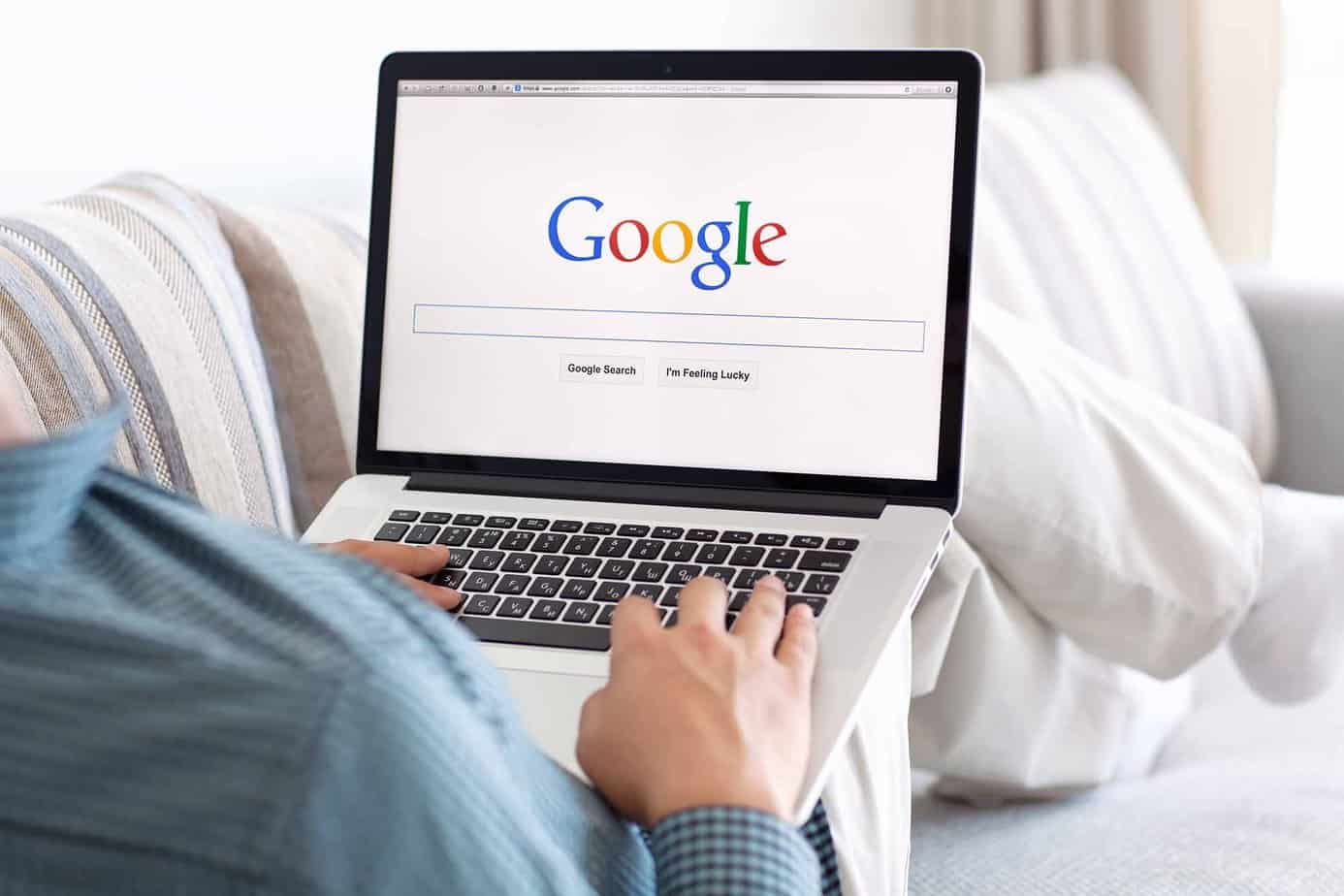 Man lying on couch doing research on google site on laptop