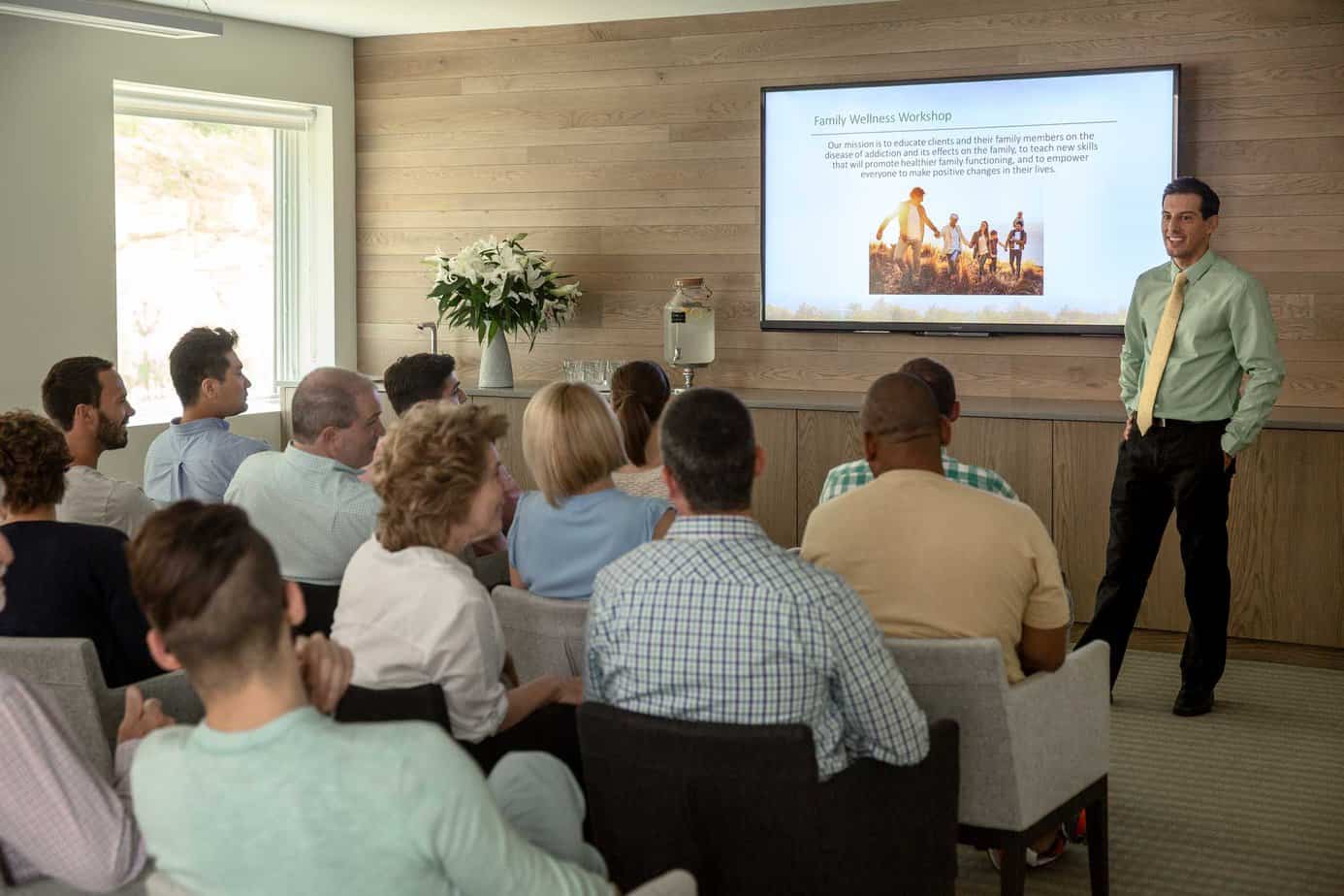 Group of patients in a family wellness workshop watching a slideshow at a Mountainside treatment facility