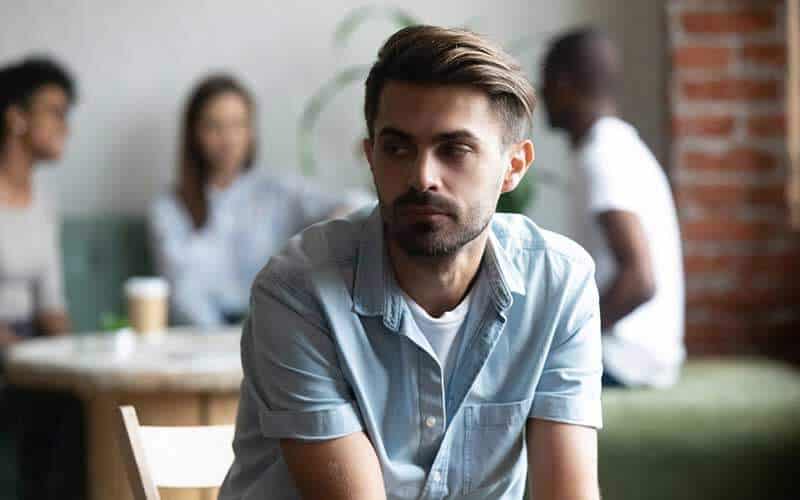 man is sitting alone and looking lonely during a social gathering