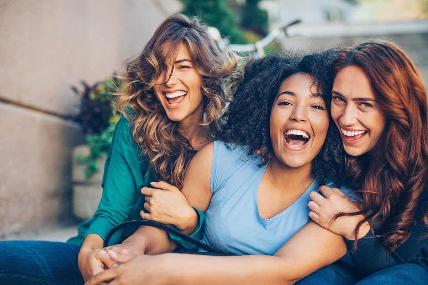 three women hugging each other smiling outside