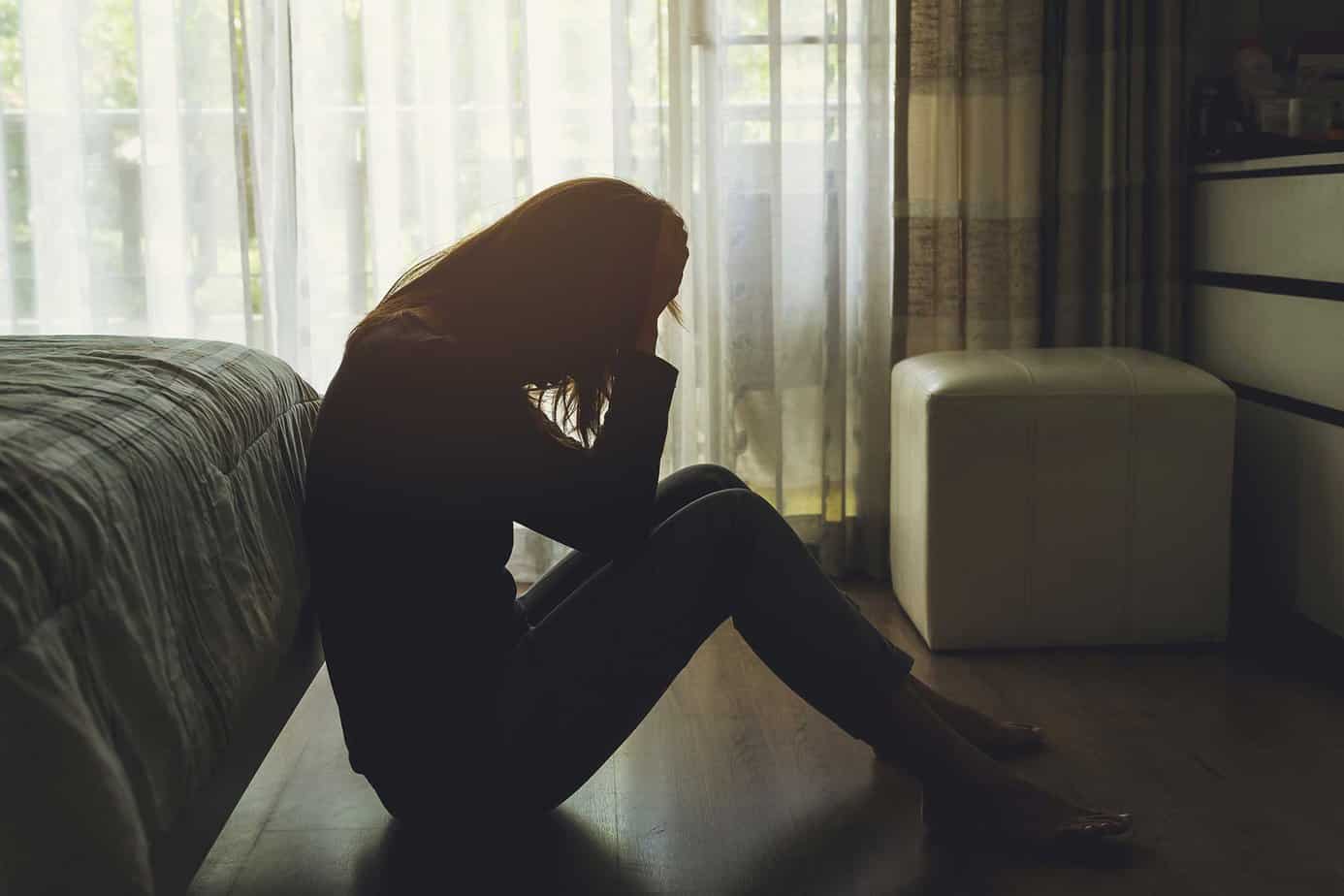woman leans against furniture in seated position, battling depression