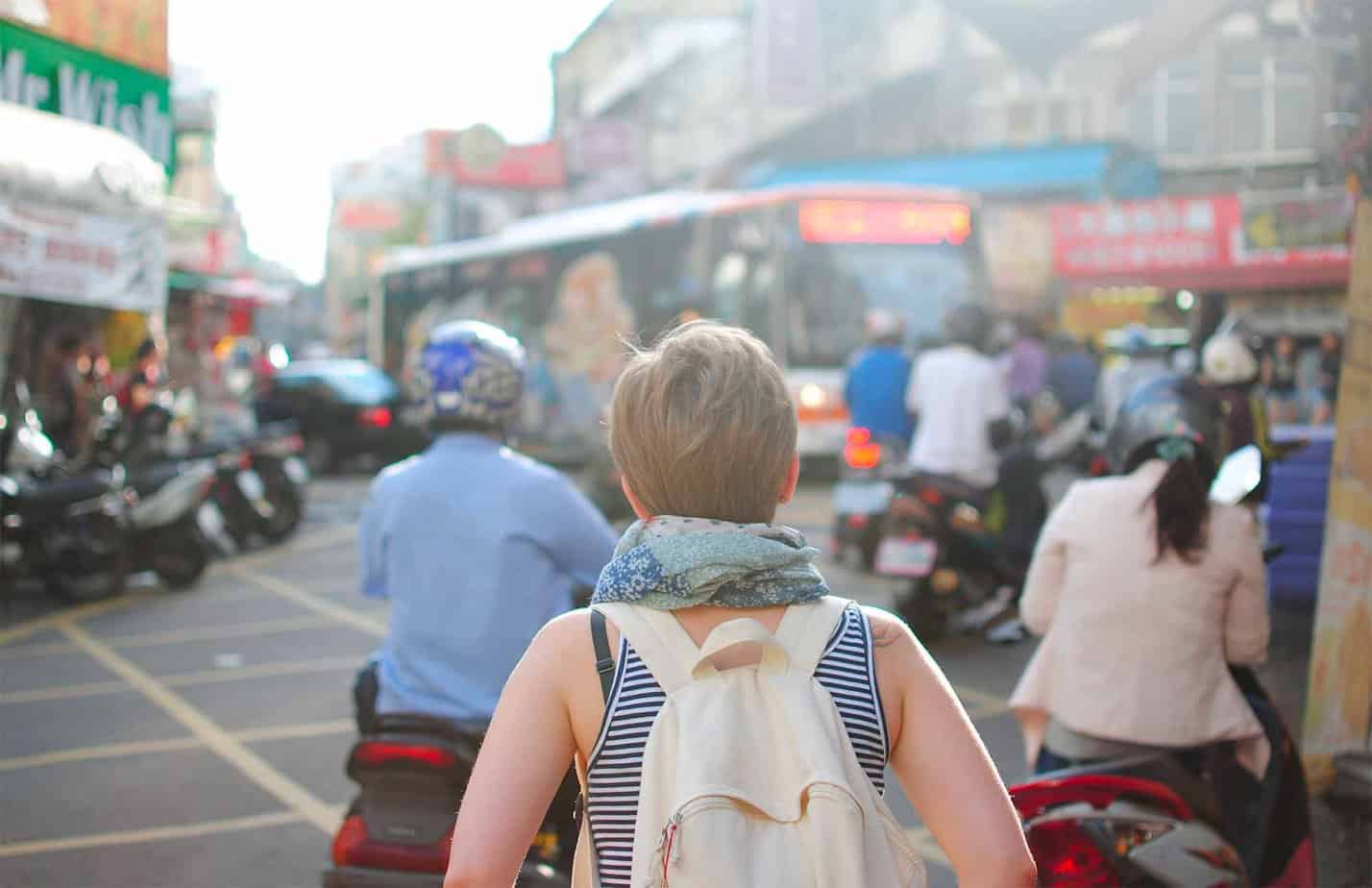 woman facing forward walking through a crowd in a city