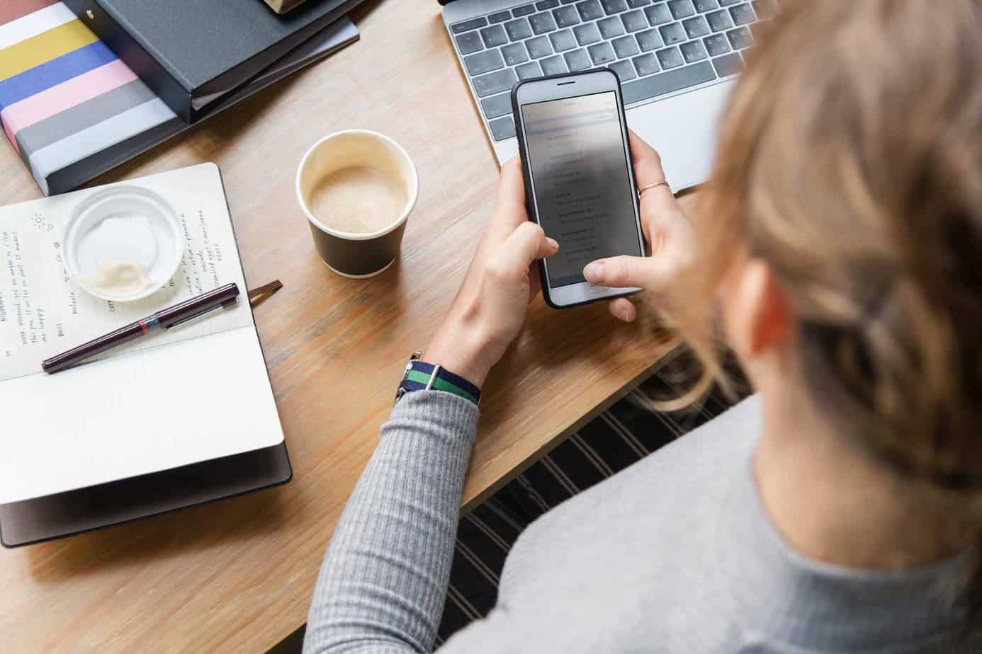 woman sitting at desk texting her friends for support