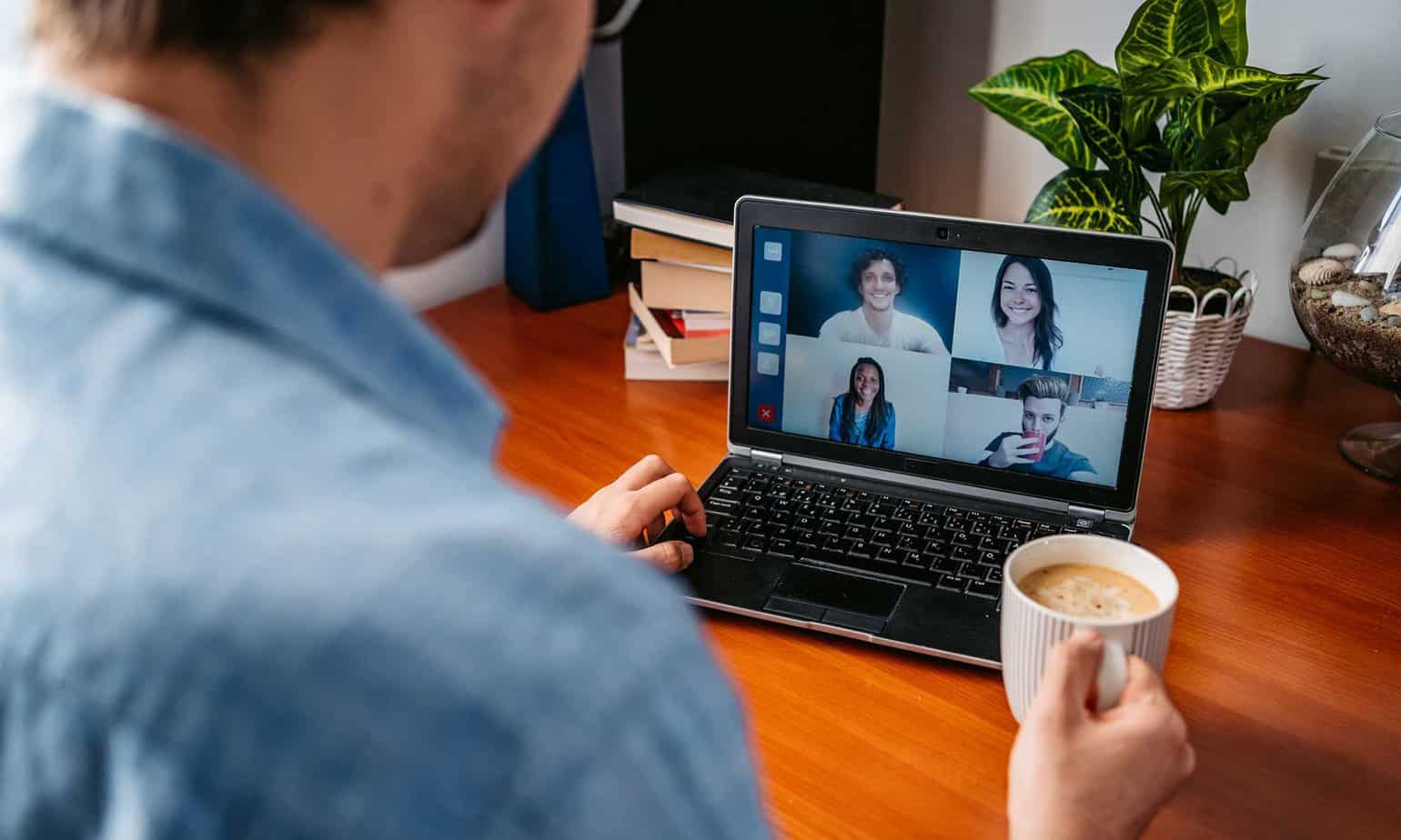 Man with cup of coffee attending an online recovery support group on his laptop