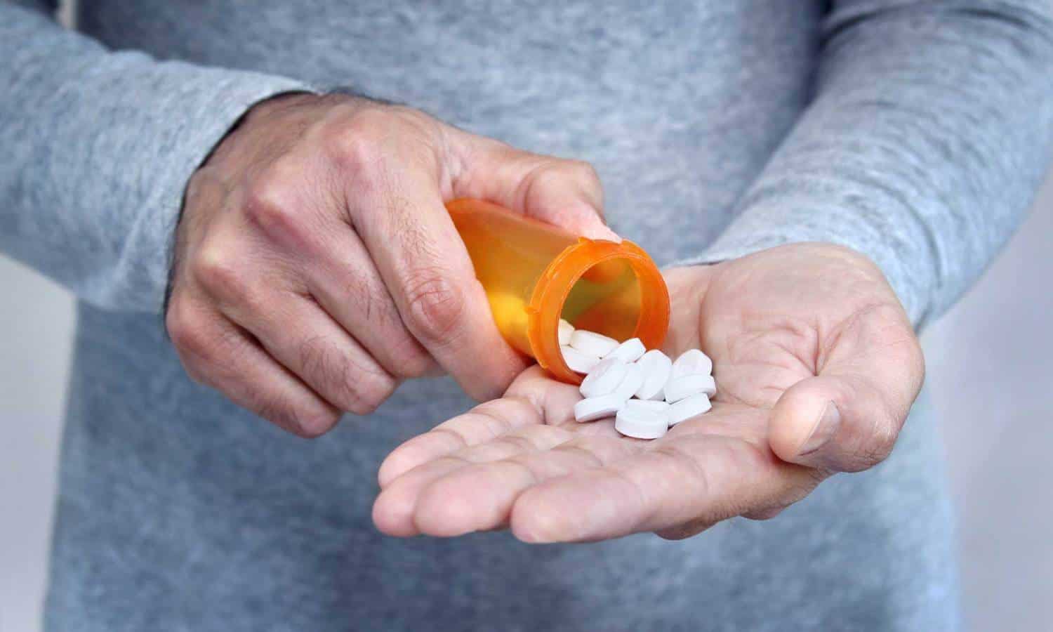A person pours out a handful of pills from a bottle for bromazolam use