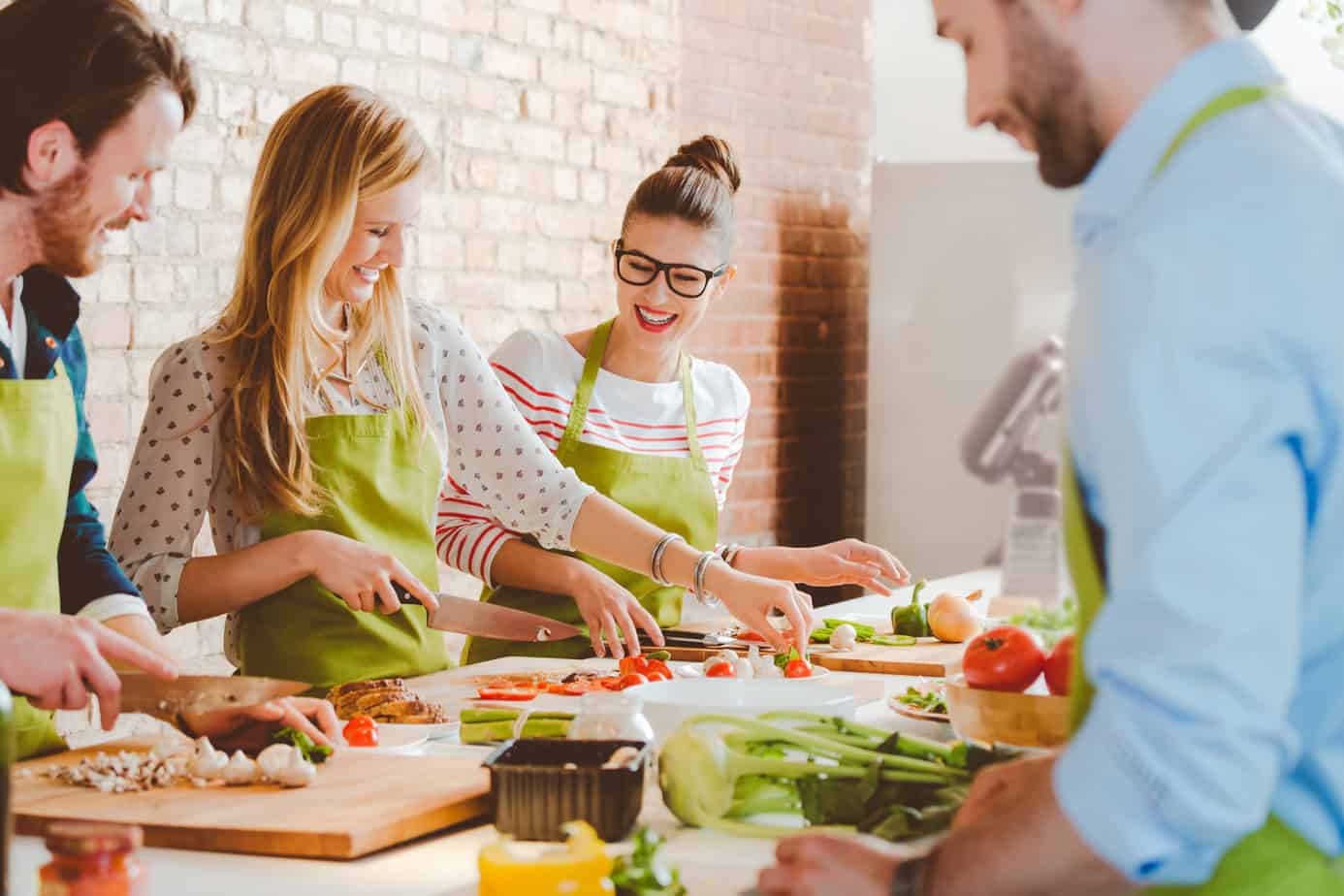four people participating in cooking class cutting vegetables and smiling