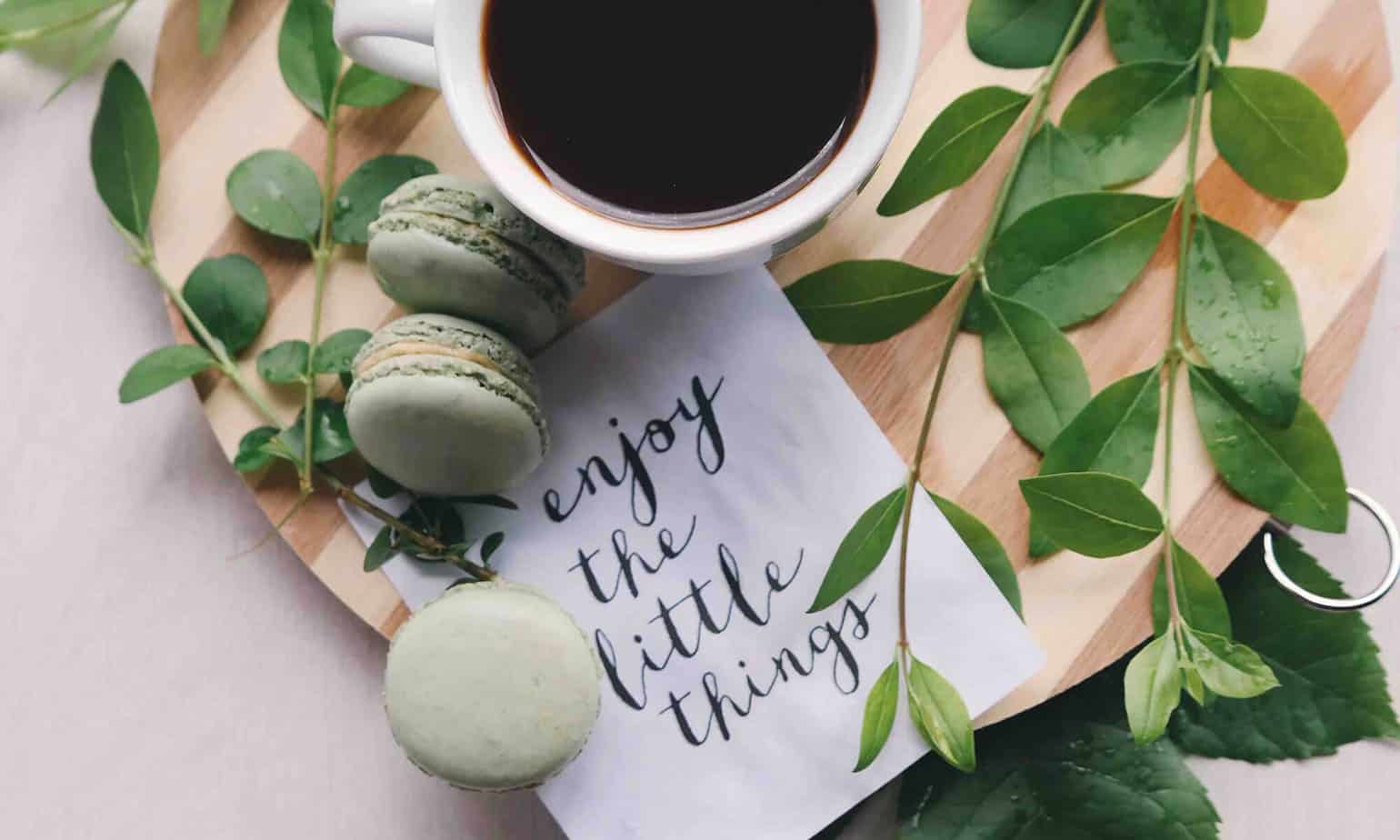 coffee on wooden board surrounded by plants and inspirational message