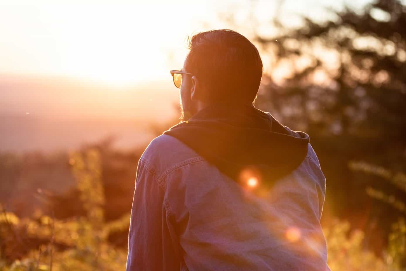 Young man on a hike watching the sunset.