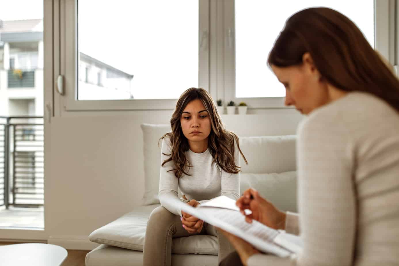 female client sitting across from doctor leaning forward and inquiring about meth detox