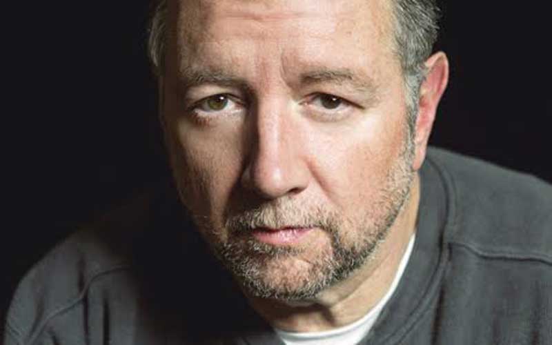man seated thoughtfully in black room