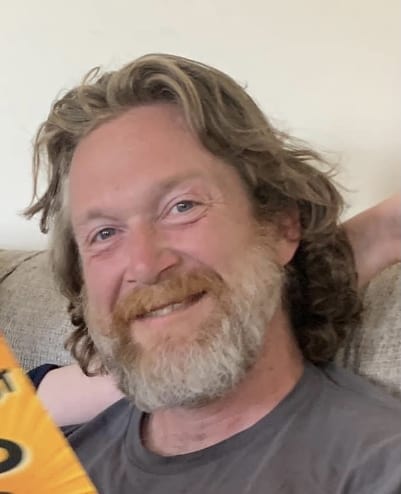 smiling bearded man sitting on couch