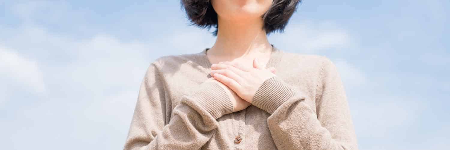 woman in cardigan with hands over center of chest