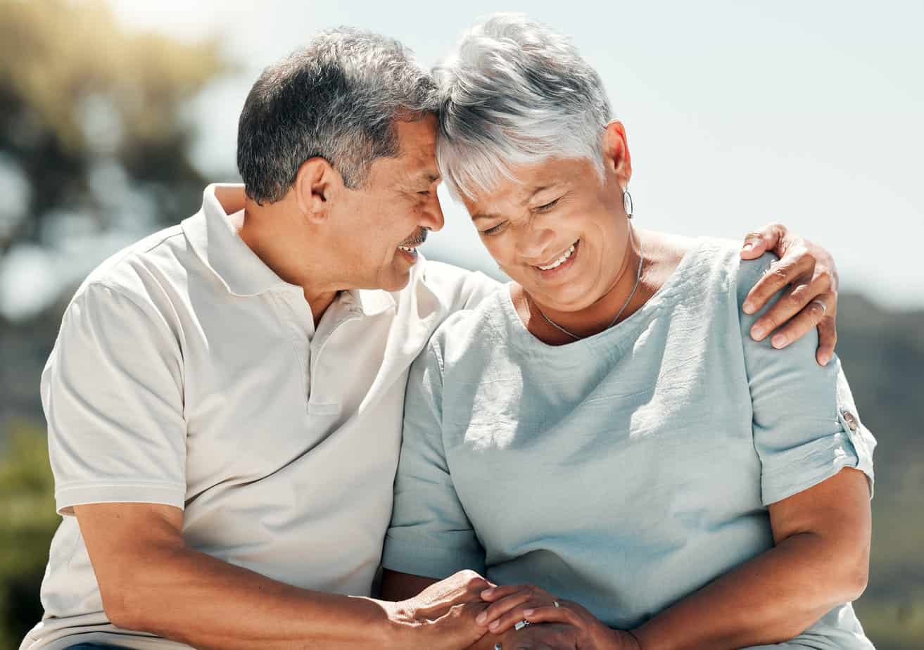 older man and woman couple embracing each other in nature