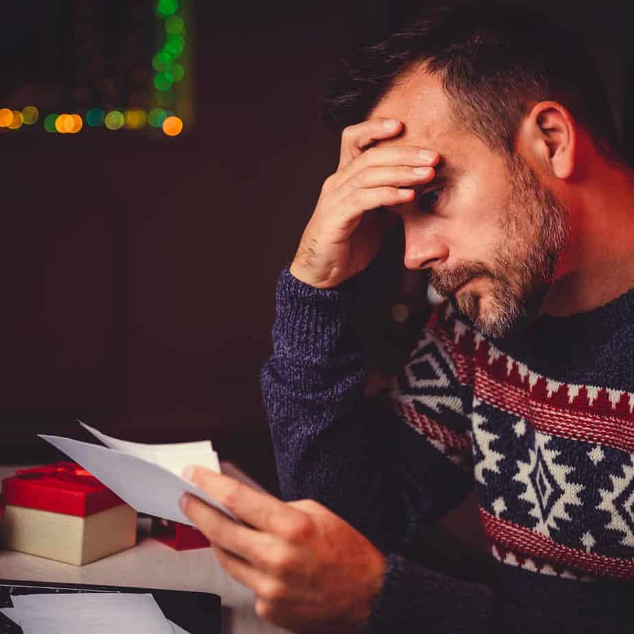 stressed man in holiday themed clothing reads letter