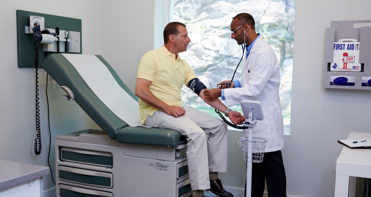 patient sits on an exam table being seen by a physician