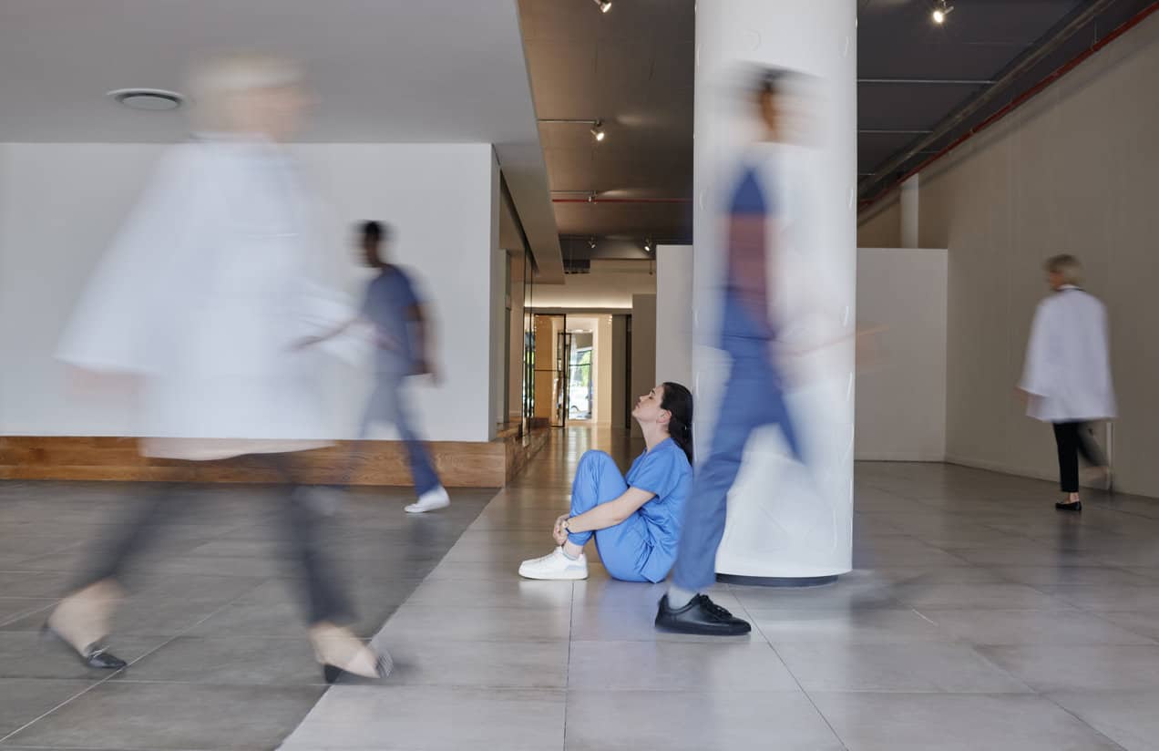 Shot of a young female doctor looking tired while working in a busy hospital.