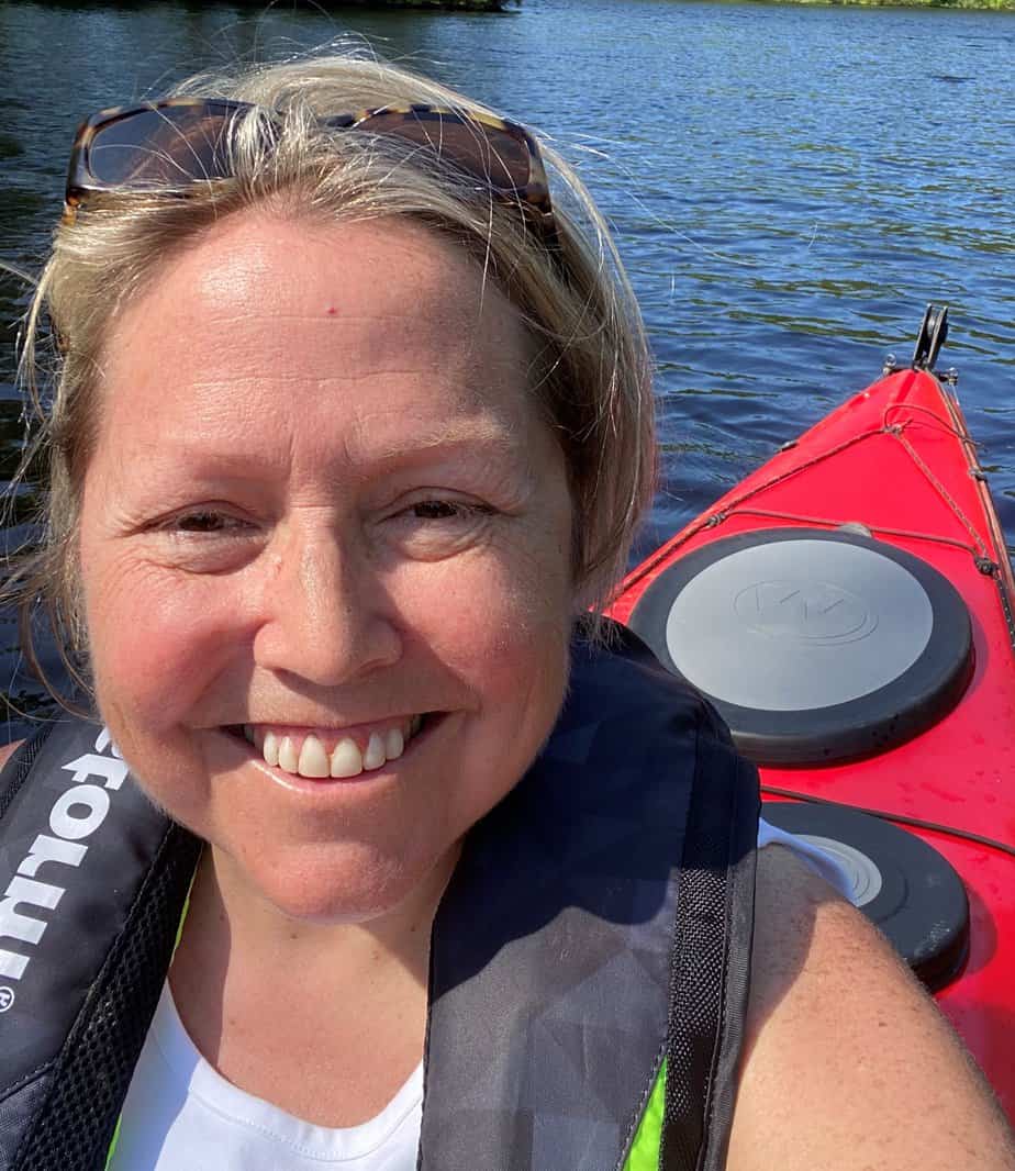 smiling blonde woman kayaking on lake