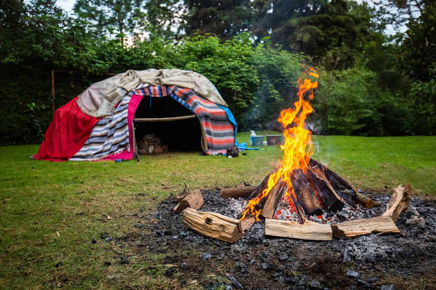 sweat lodge structure with fire in the foreground used to heat grandfather stones