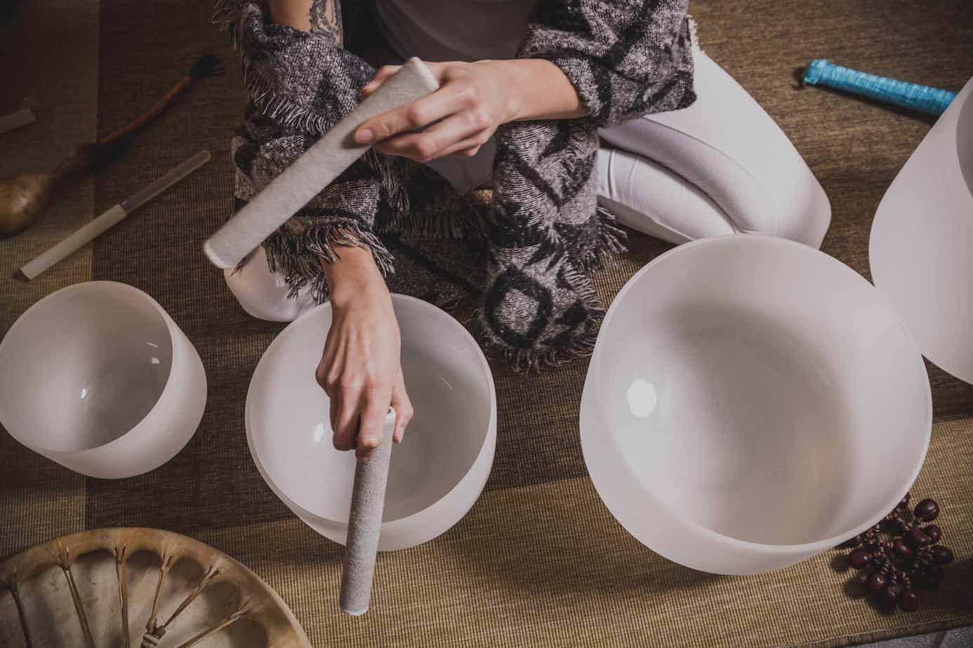 woman playing tibetan singing bowls during a sound bath session