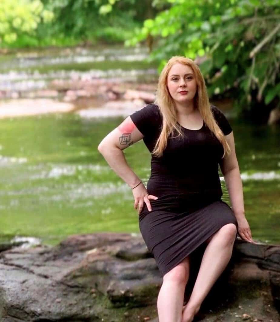 chelsea d mountainside alumni sitting on rock next to lake
