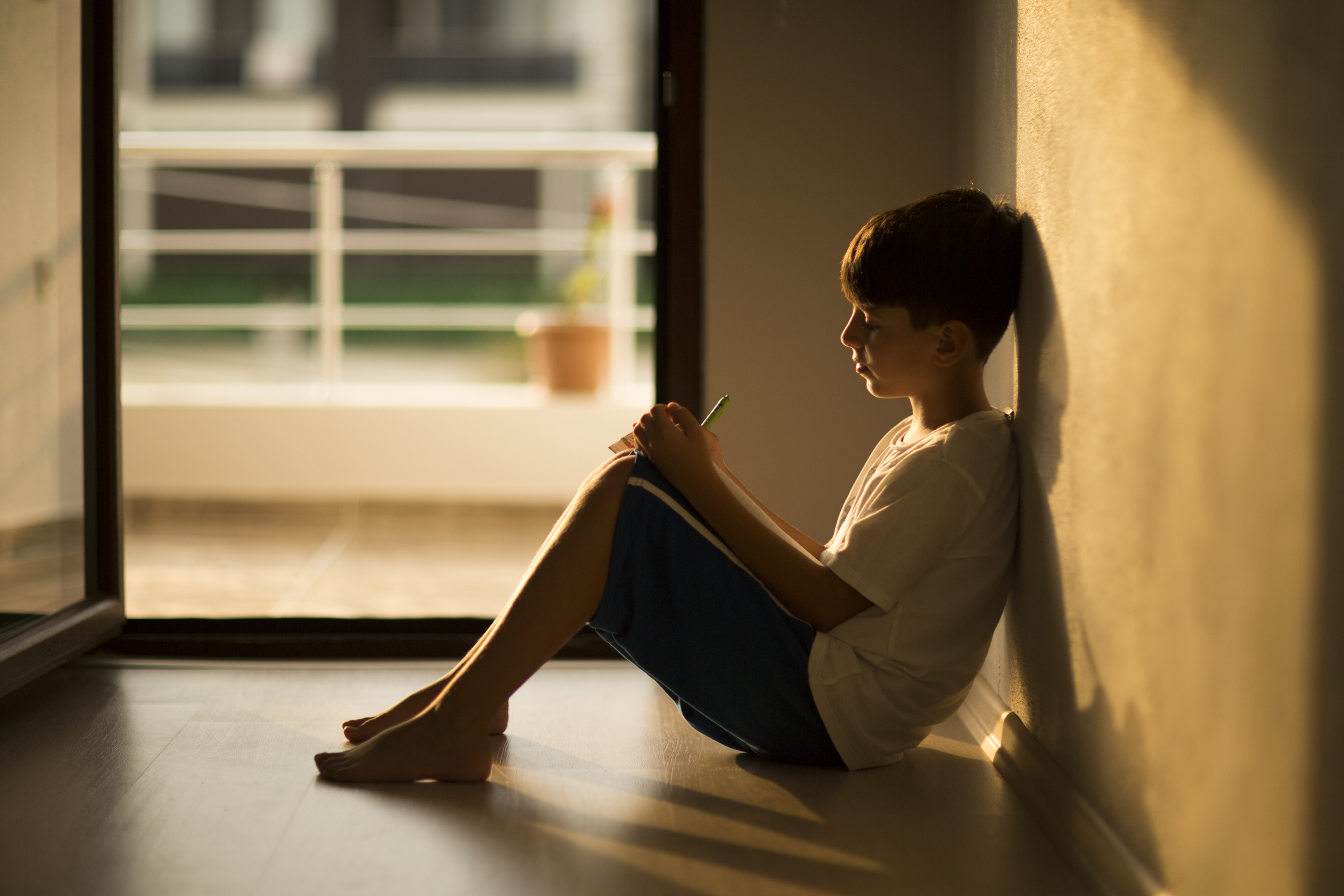 young boy sitting against the wall growing up through an adverse childhood experience (ACE)