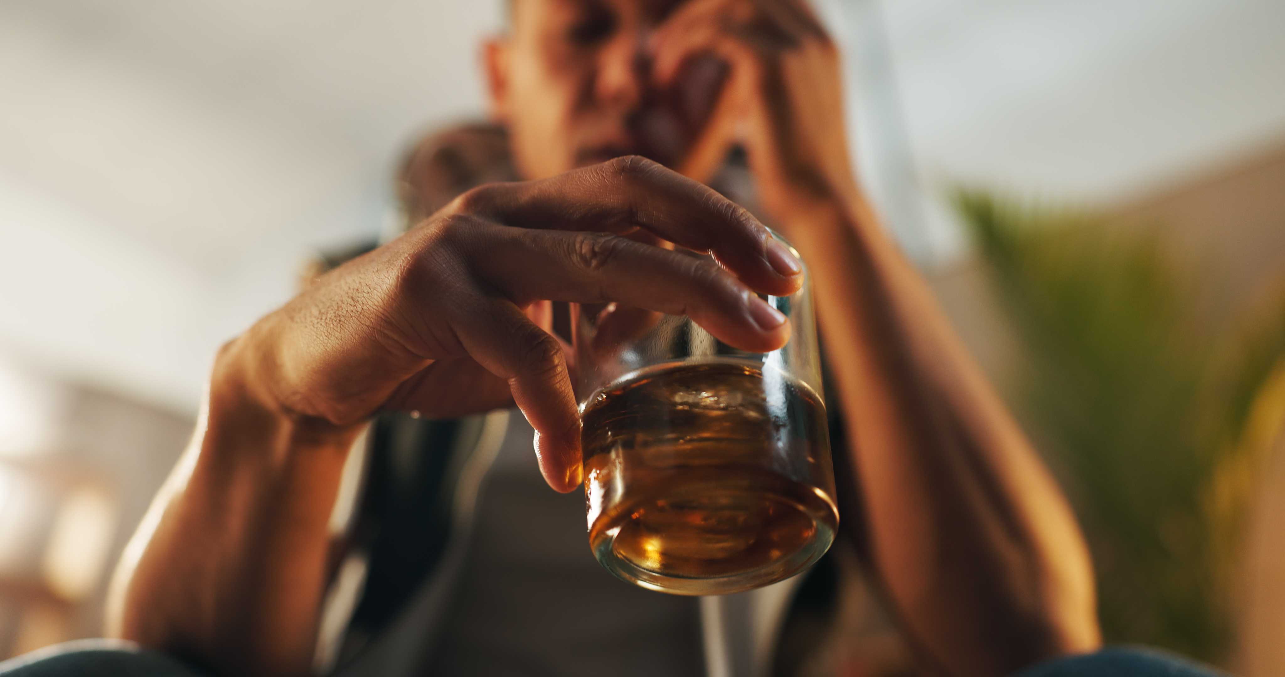 Close up of a man's hand holding a glass of alcohol.