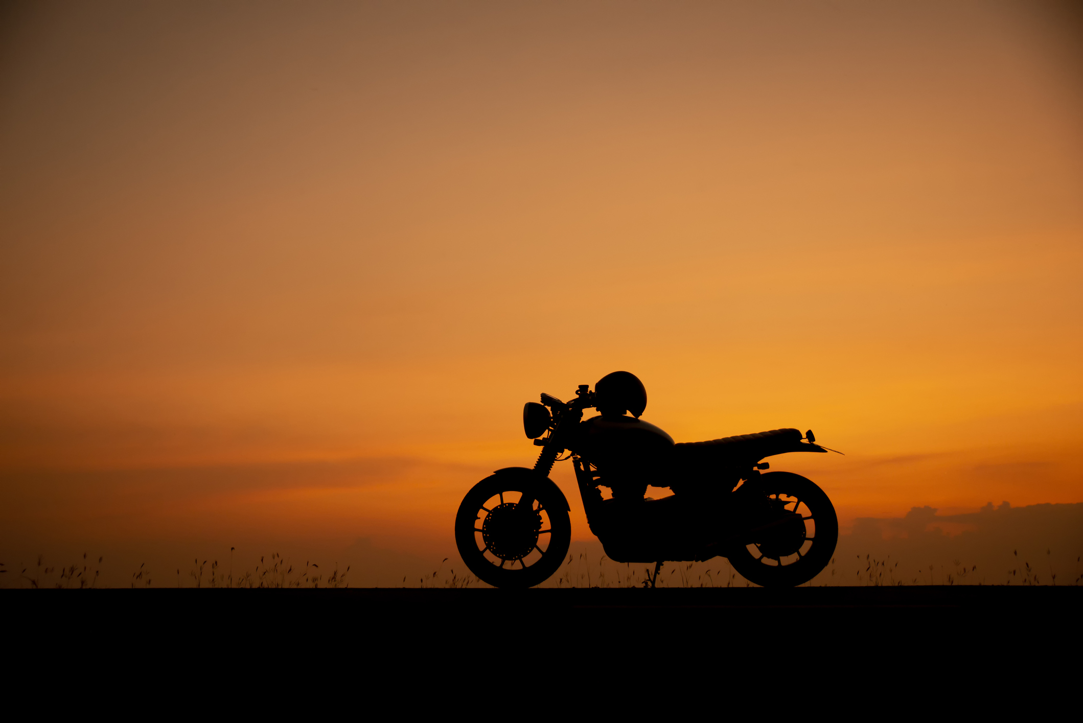 Silhouette of a motorcycle with a sunset background.