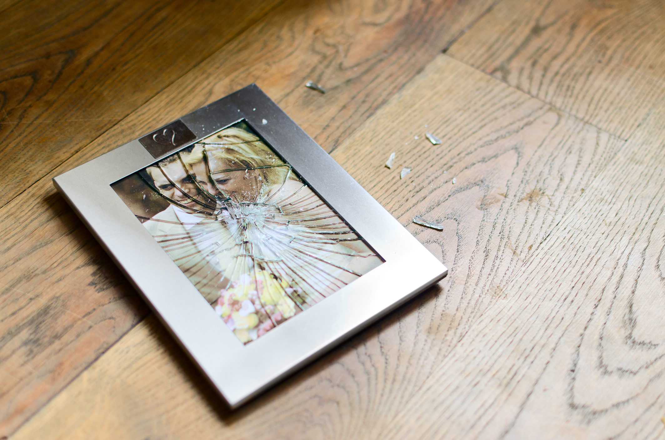 A portrait of a married couple lies on the floor with the glass in the frame shattered.