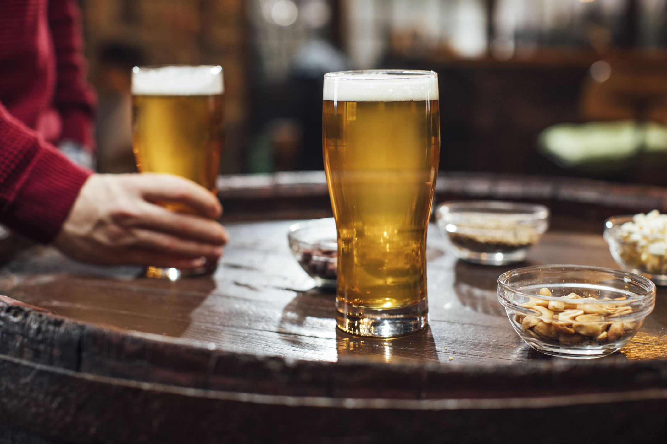 close up of man taking steroids and reaching for alcoholic beer on table next to bowl of peanuts