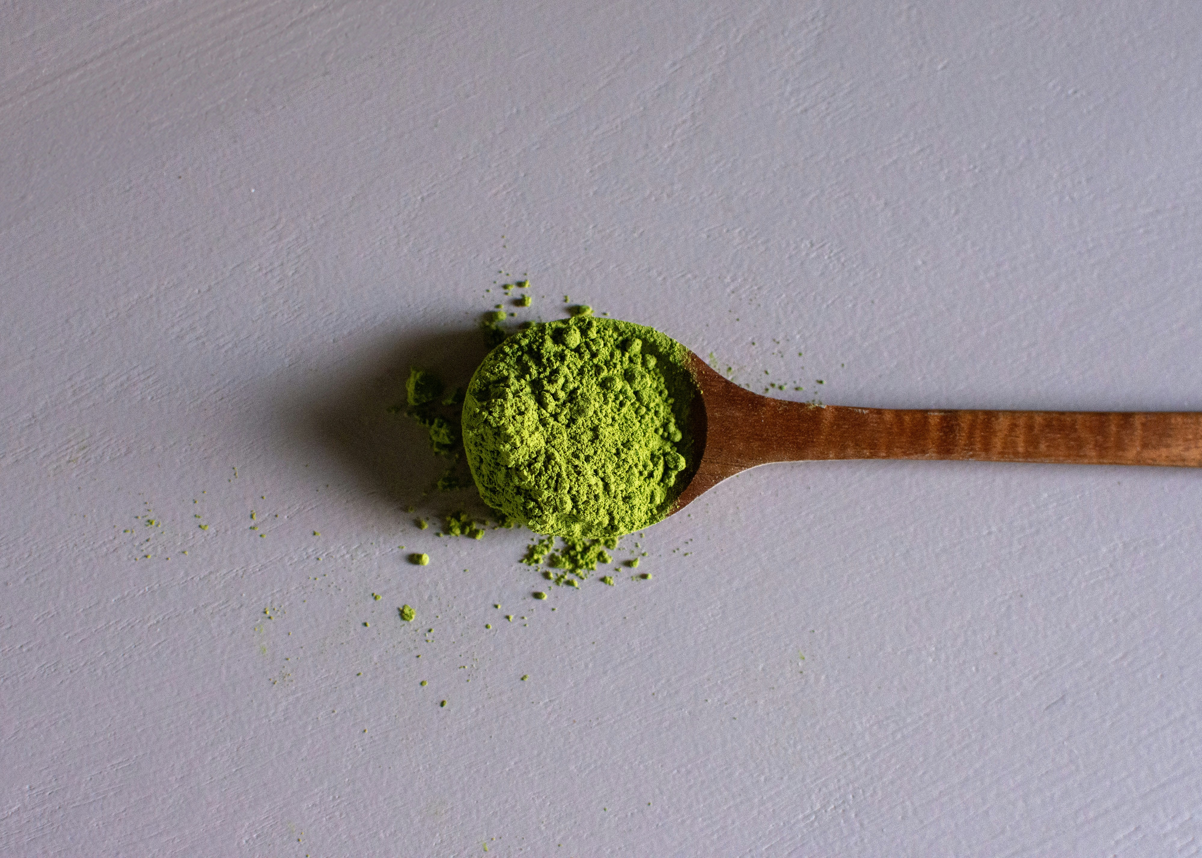 loose kratom powder in a wooden spoon