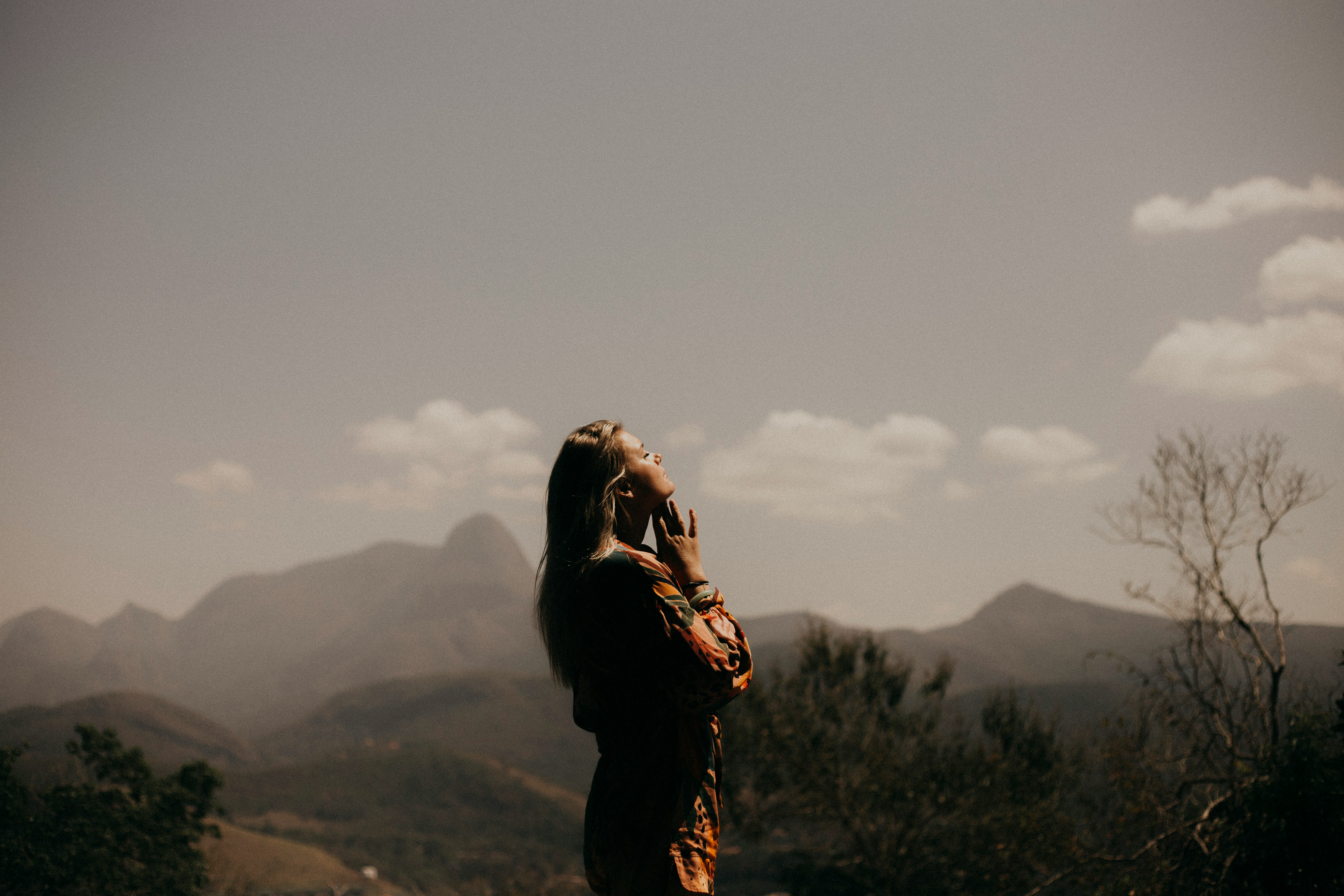 woman stands by mountains looking off into the distance practicing FBT skills